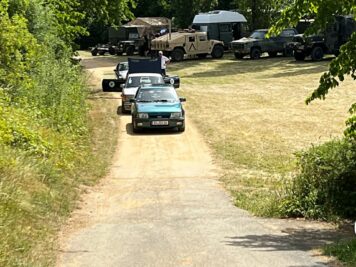 Oldtimer-Limousine in Türkis fährt auf Feldweg durch grüne Landschaft, dahinter weitere Fahrzeuge bei der ADAC Oldtimerfahrt Hessen-Thüringen