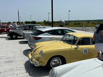 Gelber Oldtimer-Sportwagen mit Startnummer auf Parkplatz während der ADAC Oldtimerfahrt Hessen-Thüringen, weitere Fahrzeuge und Teilnehmer im Hintergrund