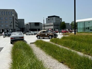 Oldtimer-Fahrzeuge auf einem Platz mit modernen Gebäuden im Hintergrund bei der ADAC Oldtimerfahrt Hessen-Thüringen