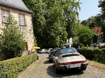 Porsche 911 mit Rallye-Streifen bei ADAC Oldtimerfahrt vor historischem Steinhaus in Hessen-Thüringen