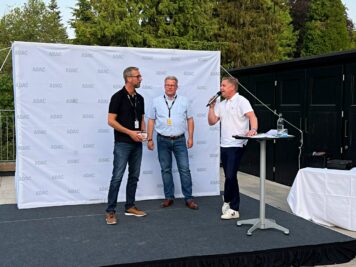 Drei Teilnehmer bei einer Podiumsdiskussion auf einer Bühne mit ADAC-Rückwand während der Oldtimerfahrt Hessen-Thüringen