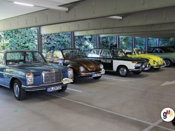 Mehrere Oldtimer unterschiedlicher Baujahre in einer Halle, darunter eine Polizeiwagen-Replik, zur ADAC Oldtimerfahrt Hessen-Thüringen