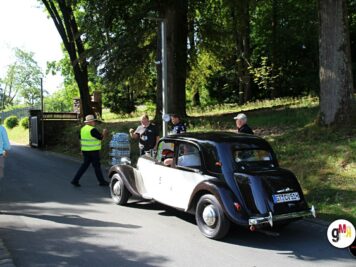 Schwarz-weißer Oldtimer-Limousine mit Blaustreifen bei Kontrollstelle der ADAC Oldtimerfahrt Hessen-Thüringen, Helfer in Warnweste begleitet Teilnehmer