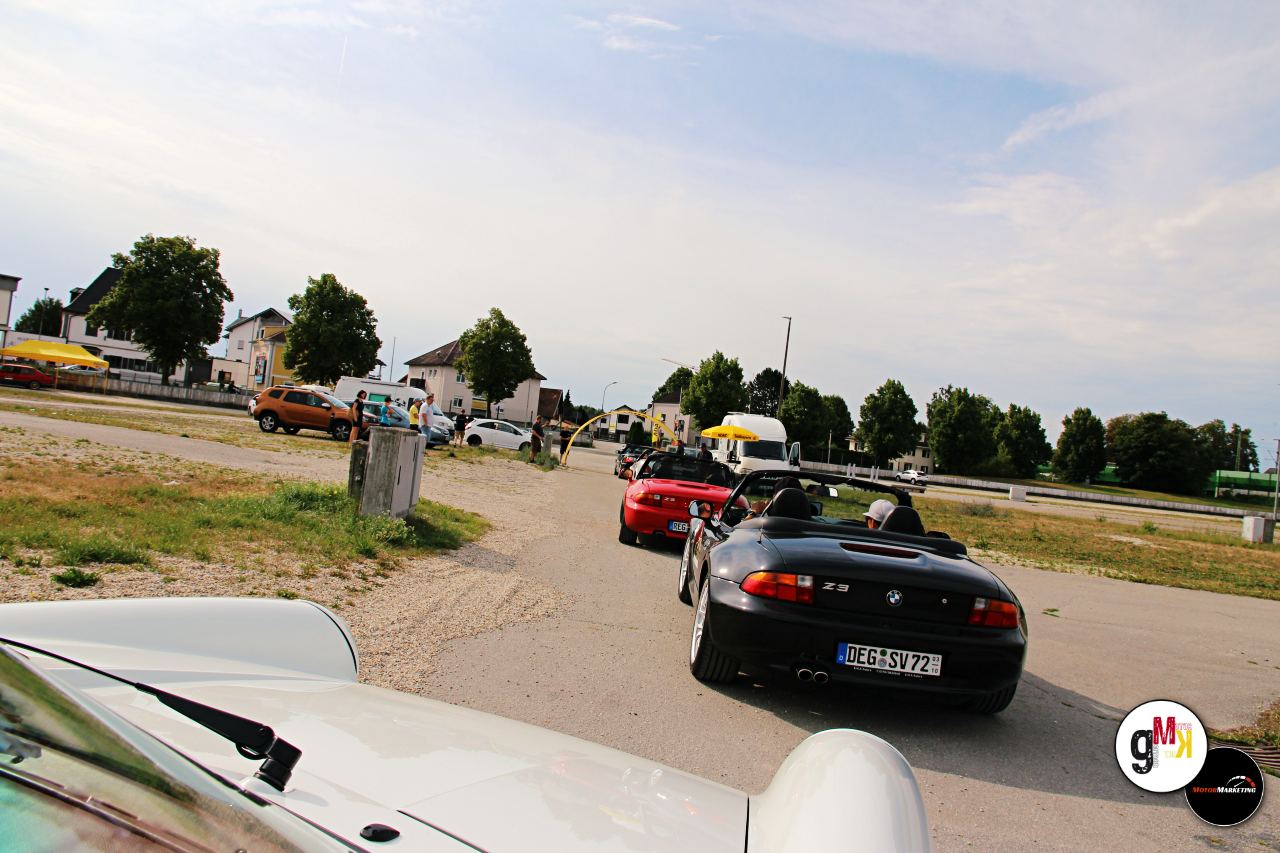 Youngtimer-Cabrios und -Limousinen stehen auf einem Parkplatz bei der ADAC Youngtimer Tour Südbayern, im Hintergrund weitere Fahrzeuge und Helfer