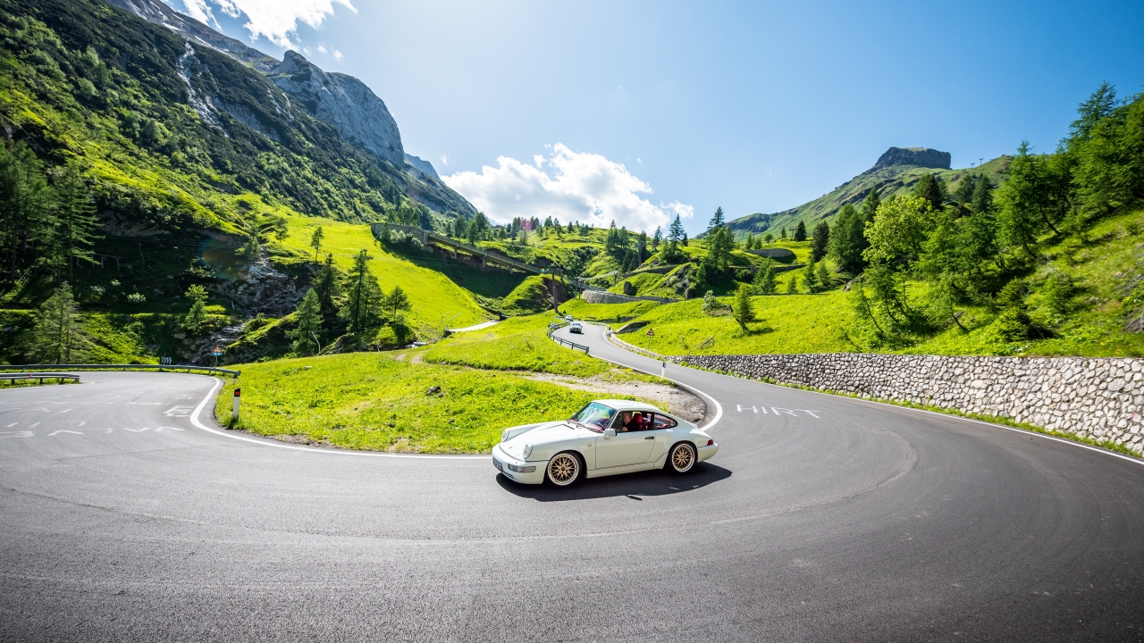 Klassischer Sportwagen auf kurviger Bergstraße in alpiner Landschaft während Oldtimer-Tour in den Dolomiten