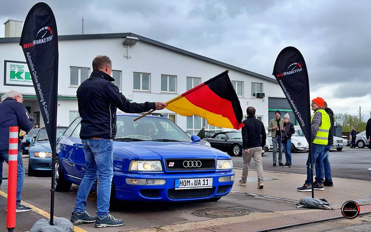 Blauer Audi-Youngtimer mit Deutschlandfahne auf dem Dach bei der ADAC Youngtimer Tour Saarland, Teilnehmer und Veranstalter an der Haltestation