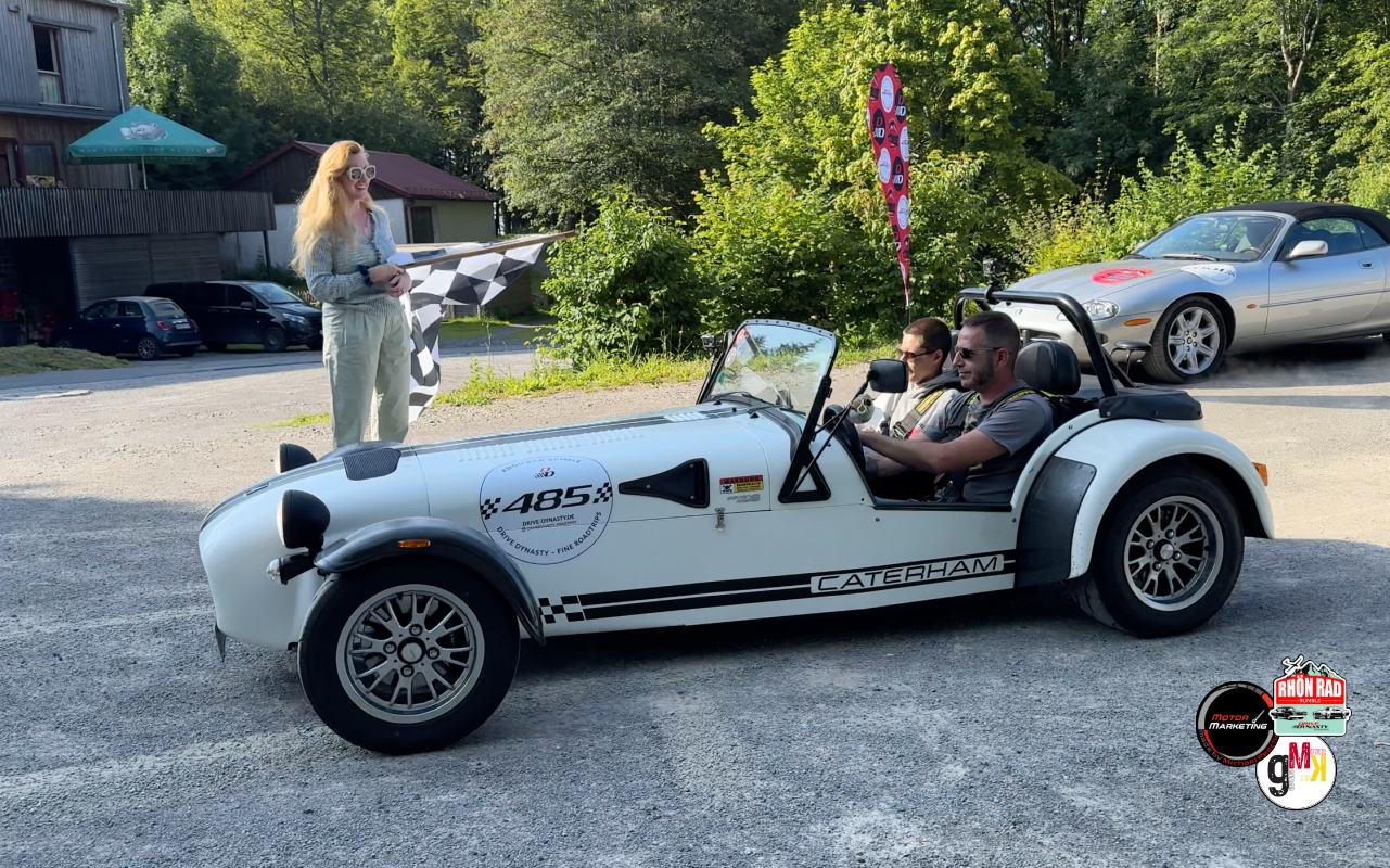 Weiße Caterham-Leichtbaureplika mit offener Karosserie und zwei Insassen während der Rhön Rad Rumble 2024