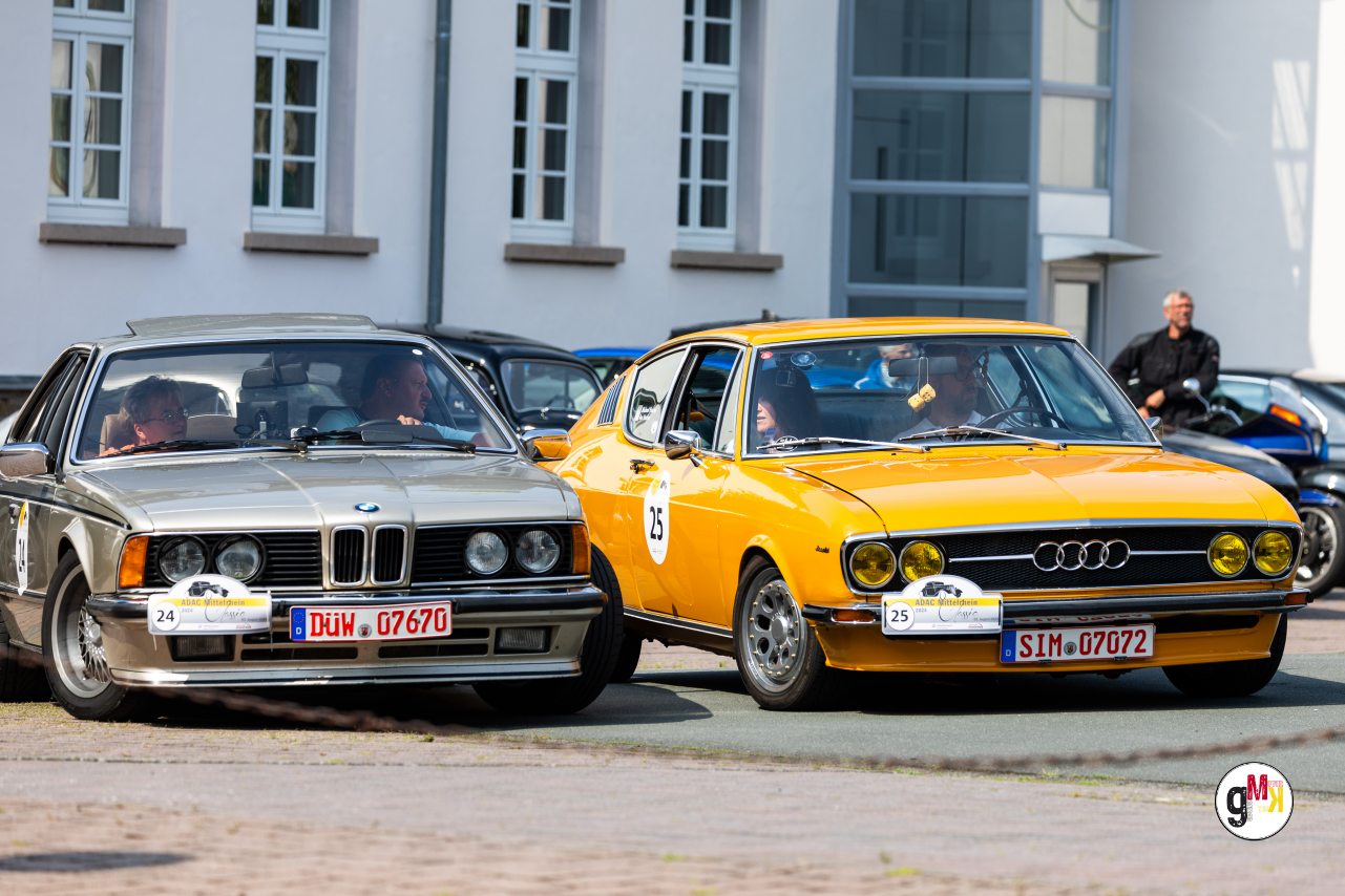 Zwei Oldtimer-Limousinen aus den 1970ern nebeneinander beim ADAC Mittelrhein-Classic 2024, links silbern mit Rallyenummern, rechts gelb-orange mit Startnummern