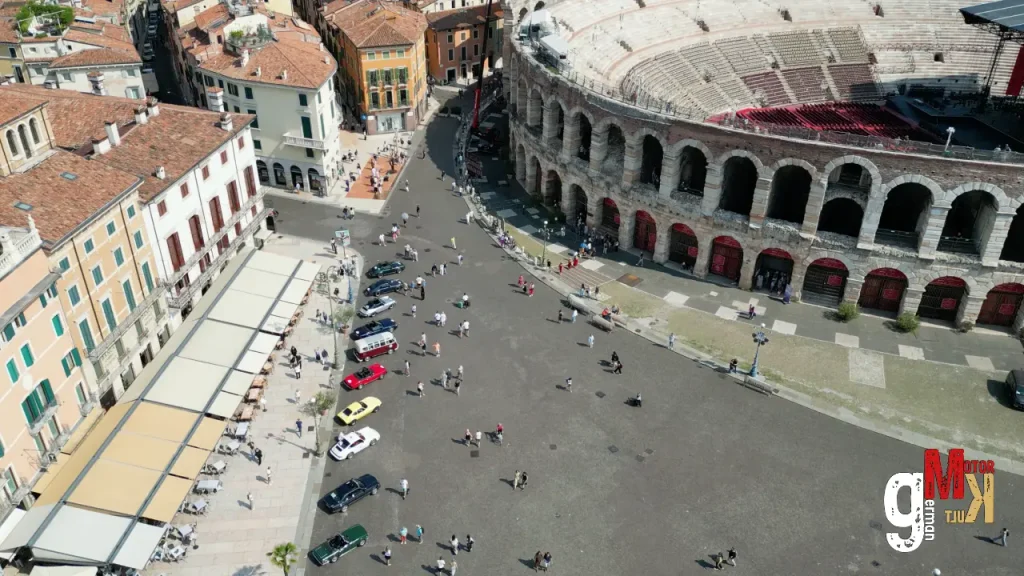 Luftaufnahme einer italienischen Altstadt mit historischem Amphitheater und geparkten Oldtimern auf dem Platz während der ADAC Gardasee Klassik
