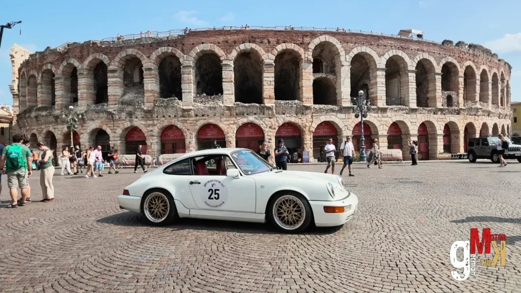 Weißer Porsche 911 mit Startnummer vor römischem Amphitheater während der ADAC Gardasee Klassik