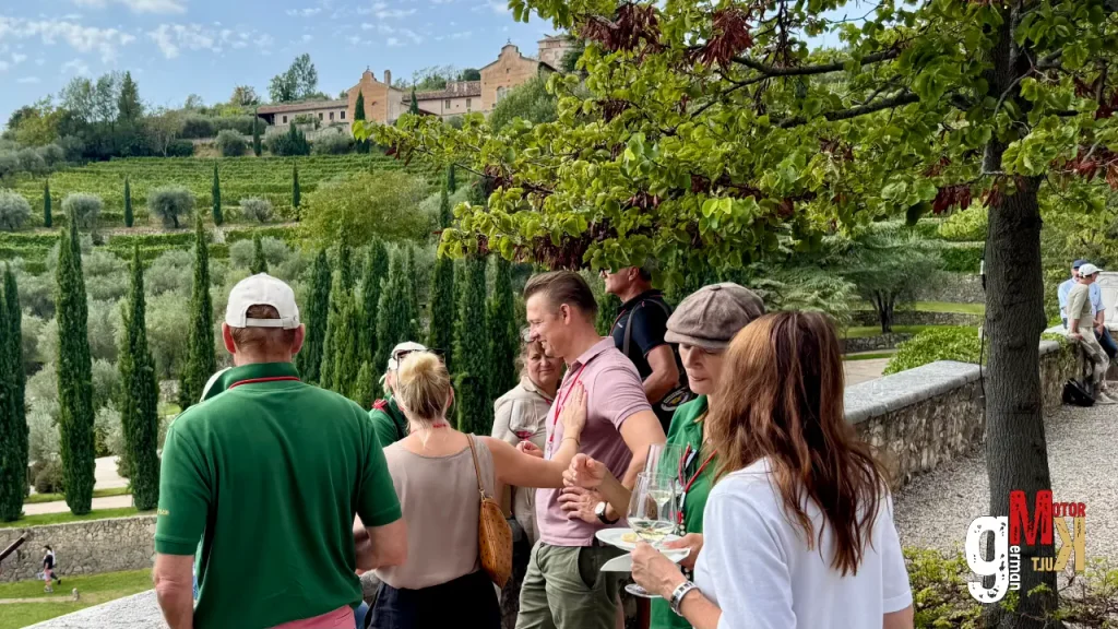 Teilnehmer der ADAC Gardasee Klassik versammeln sich in hügeliger Landschaft des Valpolicella mit historischem Dorf im Hintergrund